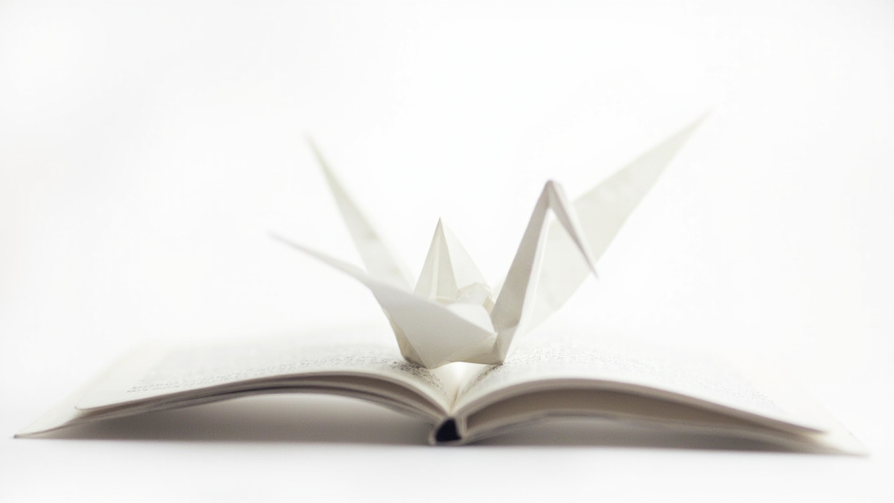 A paper origami crane unfolding and taking flight from an open book, studio lighting, white background